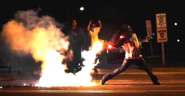 Brave young man in #Ferguson tosses a tear gas canister back toward the police officers who shot it at him.